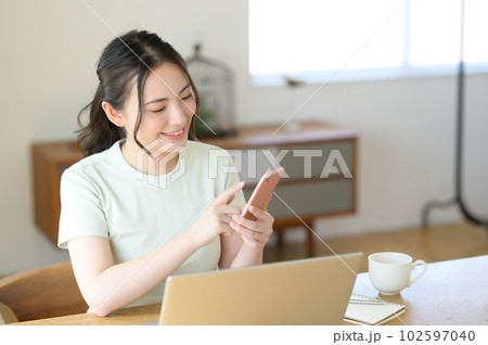 スマホを片手に操作する若い女性 102597040