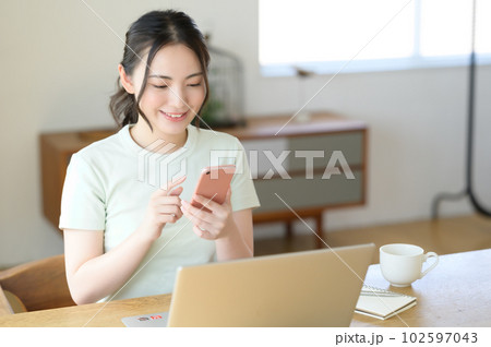 スマホを片手に操作する若い女性 102597043