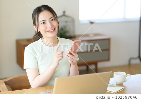 スマホを片手に操作する若い女性 102597046