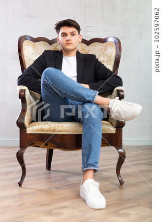 Focused young guy posing while sitting in chair 102597062