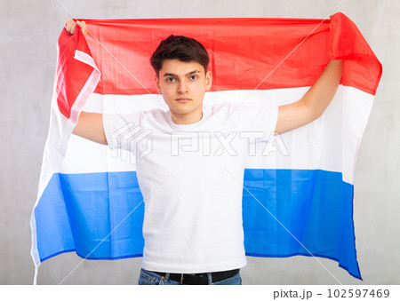 Focused young guy holding Netherlands flag 102597469