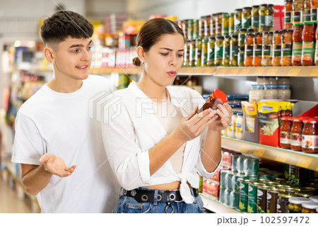 Focused interested young couple choosing sauce in supermarket Focused interested young couple choosing sauce in supermarket 102597472