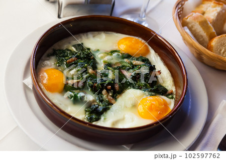 Fried eggs with spinach, ham, raisins 102597762