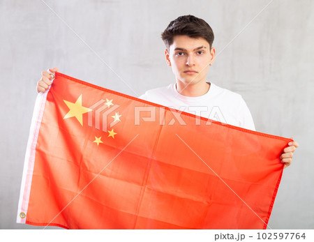 Focused young guy holding China flag Focused young guy holding China flag 102597764
