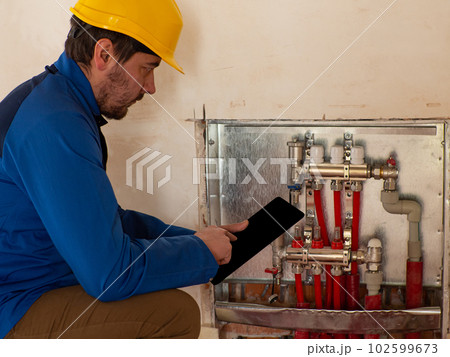 An employee adjusts the heating system via a tablet An employee adjusts the heating system via a tablet 102599673
