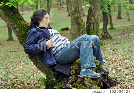 Calm pregnant woman relaxing in the forest Calm pregnant woman relaxing in the forest 102604522