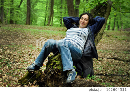 Pregnant woman relaxing on a tree trunk Pregnant woman relaxing on a tree trunk 102604531