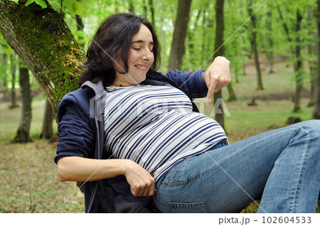 Calm pregnant woman relaxing in the forest Calm pregnant woman relaxing in the forest 102604533