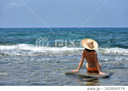 Sexy bikini tanning woman relaxing on the beach with a hat Sexy bikini tanning woman relaxing on the beach with a hat 102604574