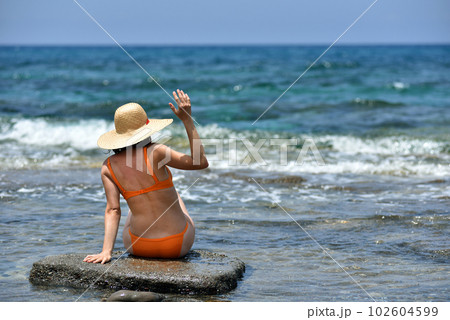 Sexy bikini tanning woman relaxing on the beach with a hat Sexy bikini tanning woman relaxing on the beach with a hat 102604599