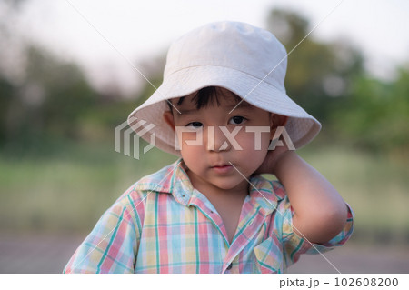 close up portrait of beautiful sweet boy, wearing White bucket hat and colorful shirt, looking at camera, big dark eyes close up portrait of beautiful sweet boy, wearing White bucket hat and colorful shirt, looking at camera, big dark eyes 102608200