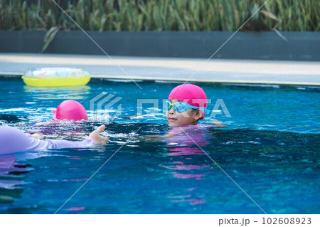 Little girl practicing swimming in the pool. Happy children swimming and playing in the water. summer vacation concept. Little girl practicing swimming in the pool. Happy children swimming and playing in the water. summer vacation concept. 102608923
