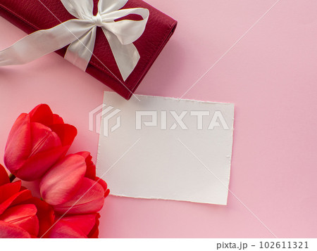 Tulips flowers, wallet with a bow and paper background with copy space Tulips flowers, wallet with a bow and paper background with copy space 102611321