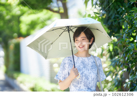 夏の日差しの中日傘を差して歩くミドル女性 夏の日差しの中日傘を差して歩くミドル女性 102612306