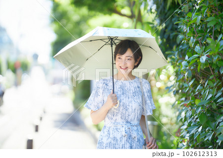 夏の日差しの中日傘を差して歩くミドル女性 102612313