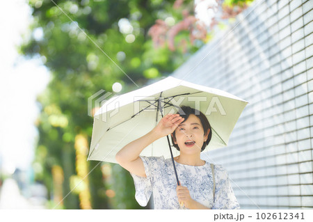 夏の日差しの中日傘を差して歩くミドル女性 夏の日差しの中日傘を差して歩くミドル女性 102612341