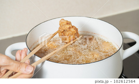 鶏の唐揚げ・調理シーン｜揚がった唐揚げを油から取り出す 102612564