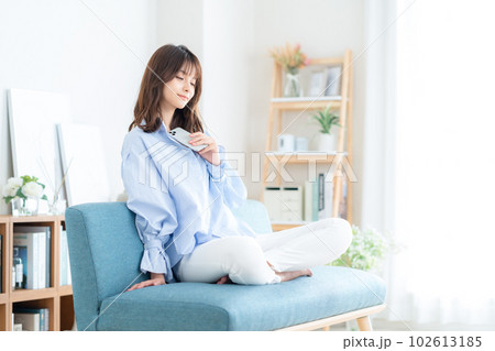 リビングのソファでスマホを操作する若い女性 リビングのソファでスマホを操作する若い女性 102613185