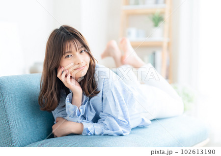 リビングでソファで寝転んでくつろぐ若い女性 リビングでソファで寝転んでくつろぐ若い女性 102613190