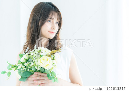 窓際でブーケを持つ若い花嫁 102613215