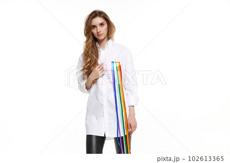 Portrait of young pretty girl in wearing white shirt with rainbow line symbolizing lgbt support. Model posing against white background 102613365