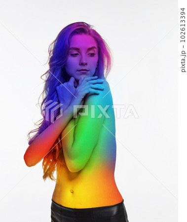 Portrait of young tender girl standing shirtless with body colored in rainbow colors against white background. Lgbt Portrait of young tender girl standing shirtless with body colored in rainbow colors against white background. Lgbt 102613394