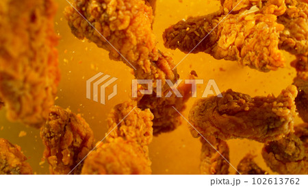 Freeze Motion Shot of Flying Fresh Fried Chicken Wings or Strips, Close-up Freeze Motion Shot of Flying Fresh Fried Chicken Wings or Strips, Close-up 102613762