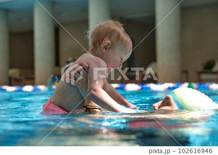 Caring mother, smiling, holding cute with little kid, girl, daughter in swimming pool indoors on warm sunny day Caring mother, smiling, holding cute with little kid, girl, daughter in swimming pool indoors on warm sunny day 102616946
