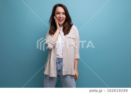 charming young dark-haired lady in informal clothes smiling on blue background charming young dark-haired lady in informal clothes smiling on blue background 102619299