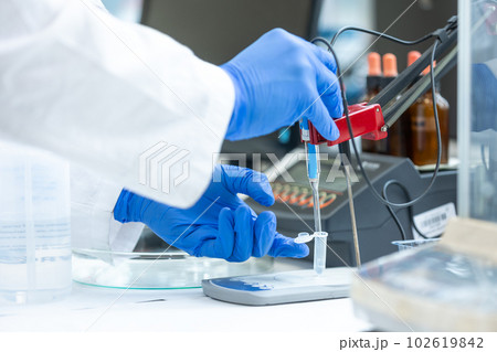 Laboratory technician holding glass electrode for measuring of pH of the solution using a pH meter., analytical or electro chemistry laboratory, lab concept 102619842