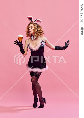 Portrait with young beautiful girl, woman wearing funny dress holding glass of beer over pink background. Concept of drinks, alcohol, Oktoberfest 102619843