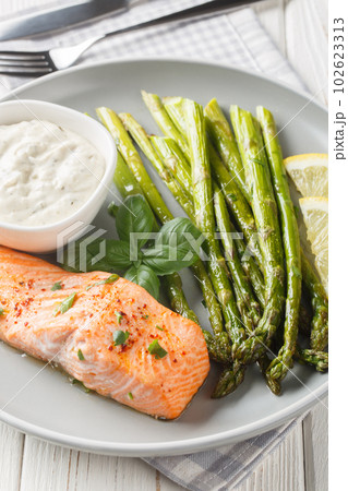 Baked salmon fillet with asparagus served with tartar sauce close-up in a plate. Vertical Baked salmon fillet with asparagus served with tartar sauce close-up in a plate. Vertical 102623313