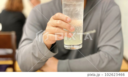 飲食店でチューハイを飲む男性の手元 102623466