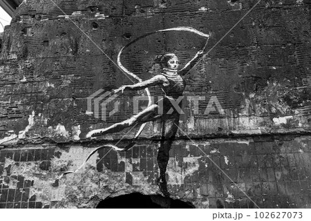 IRPIN, UKRAINE - NOVEMBER 29, 2022: Gymnast with ribbon - Banksy graffiti in Irpin, Ukraine, black and white photo IRPIN, UKRAINE - NOVEMBER 29, 2022: Gymnast with ribbon - Banksy graffiti in Irpin, Ukraine, black and white photo 102627073
