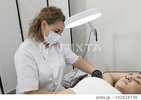 Electrologist Doing Underarm Hair Removal Procedure With Electrolysis To White Young Woman, Electric Epilation In Beauty Salon. Horizontal Plane. Authentic Photo Electrologist Doing Underarm Hair Removal Procedure With Electrolysis To White Young Woman, Electric Epilation In Beauty Salon. Horizontal Plane. Authentic Photo 102628736