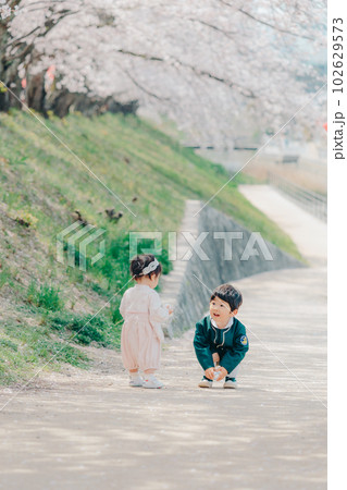 桜並木を歩く兄弟2人の写真 102629573