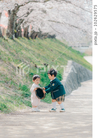 桜並木を歩く兄弟2人の写真 102629575