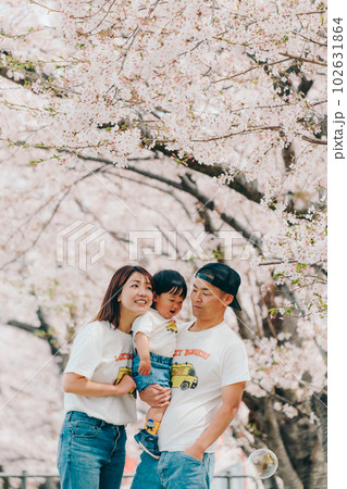 桜の木の下で佇む家族3人の写真 102631864