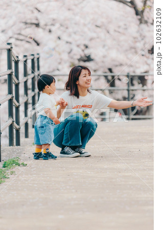 桜バックに子供を抱っこするお母さん 102632109