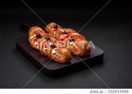 Delicious fresh crispy pastry in the form of a pigtail with strawberries and blueberries Delicious fresh crispy pastry in the form of a pigtail with strawberries and blueberries 102633998