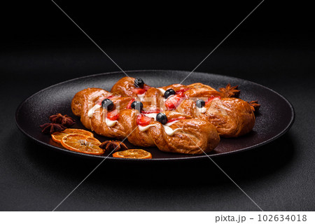 Delicious fresh crispy pastry in the form of a pigtail with strawberries and blueberries 102634018