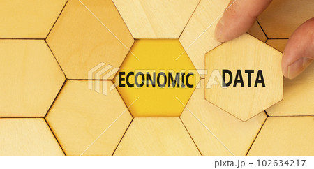 Economic data symbol. Concept words Economic data on wooden puzzles. Beautiful yellow table yellow background. Businessman hand. Business economic data concept. Copy space. 102634217