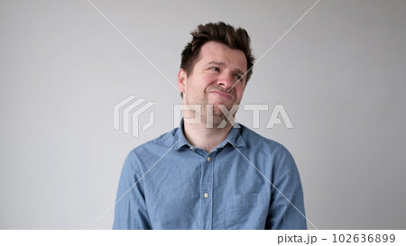 European young man is hesitating and unwilling to make decisions. He is upset about having to do unpleasant work. 102636899
