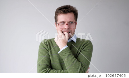 A European young man is nervous and biting his nails. A European young man is nervous and biting his nails. 102637406
