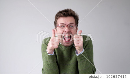 European young man shows a thumbs up. He is thrilled with the result European young man shows a thumbs up. He is thrilled with the result 102637415