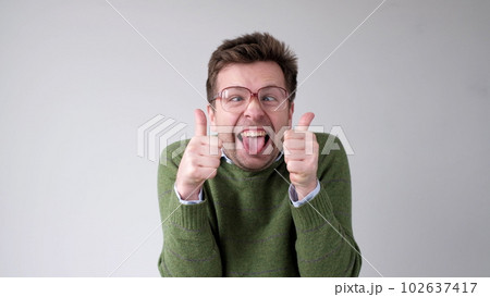 European young man shows a thumbs up. He is thrilled with the result European young man shows a thumbs up. He is thrilled with the result 102637417