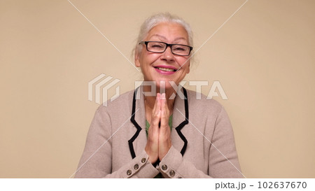 An elderly European woman is praying for help, holding her palms together. Do me a favor 102637670