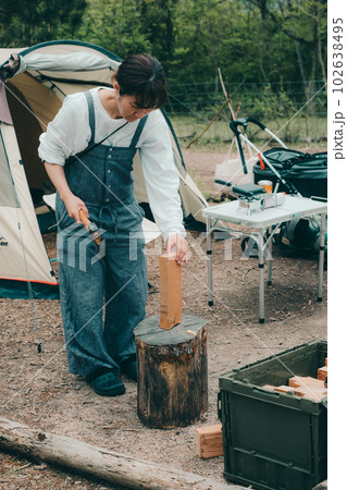 女性ソロキャンプで薪割りをする 102638495