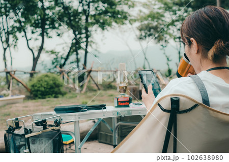 女性ソロキャンプでスマホを触る 102638980