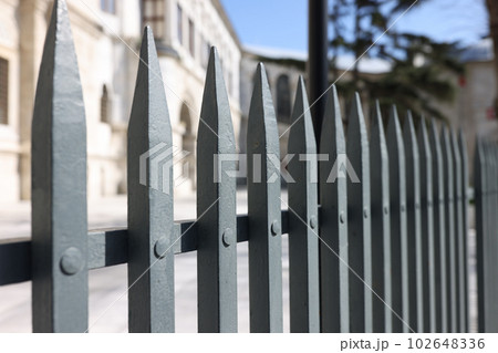 Spiky jagged metal fence against old building on city street 102648336